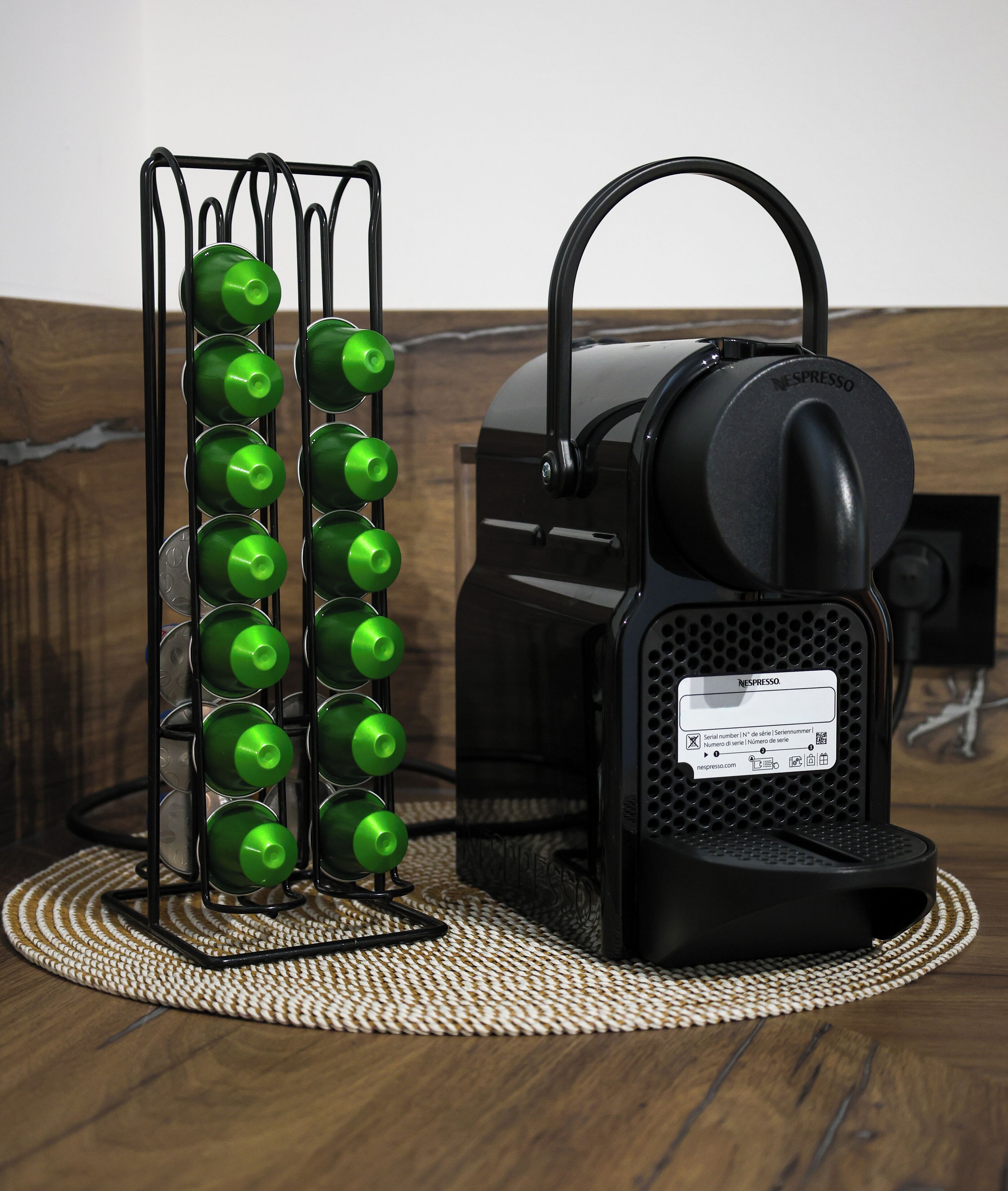 Een Nespresso koffieapparaat met een groene fleshouder ernaast.