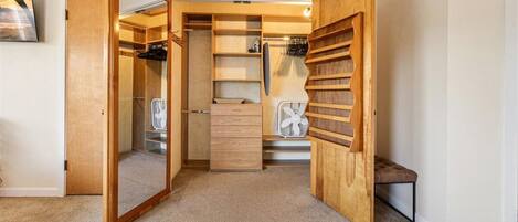 A walk-in closet with open doors, shelves, and a bench.