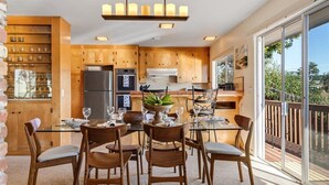 Une cuisine moderne avec des meubles en bois, un îlot central et un coin repas comprenant des chaises et une table.