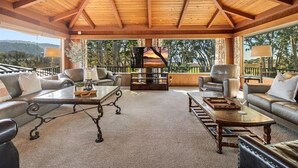 Un espace extérieur aménagé, abrité et doté de canapés en cuir, d’une table basse en bois et offrant une vue sur le paysage environnant.