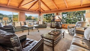 Un vaste espace de vie agrémenté de canapés en cuir, d’une table basse et d’une cheminée.