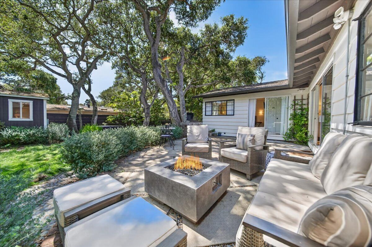 A patio area with outdoor furniture, a fire pit, and a view of a house.