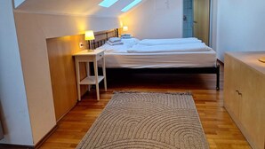 A bedroom with a bed, bedside lamps, a small table, a cabinet, a door, and a skylight. - Dorf Apart & Dorf Cafe Appartements (Neustift Im Stubaital)