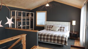 A bedroom with a bed, a wooden headboard, a window with blinds, a bedside table with a lamp, and a star decoration on the wall.