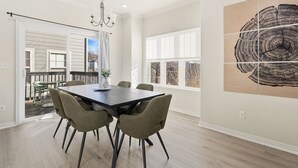 A dining area with a large table and chairs, a chandelier, and a large window with a view. - The Encore - 2 mi to Amp - 1 mi to Promenade (Rogers)