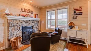 A cozy living room with a stone fireplace, leather sofa, and a large window. - New Listing! National Forest Access + Hot Tub | Continental Divide | Deck (Fairplay)
