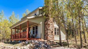 A two-story house with a stone chimney, a covered porch with a red railing, and a stone staircase leading to the front door. - New Listing! National Forest Access + Hot Tub | Continental Divide | Deck (Fairplay)