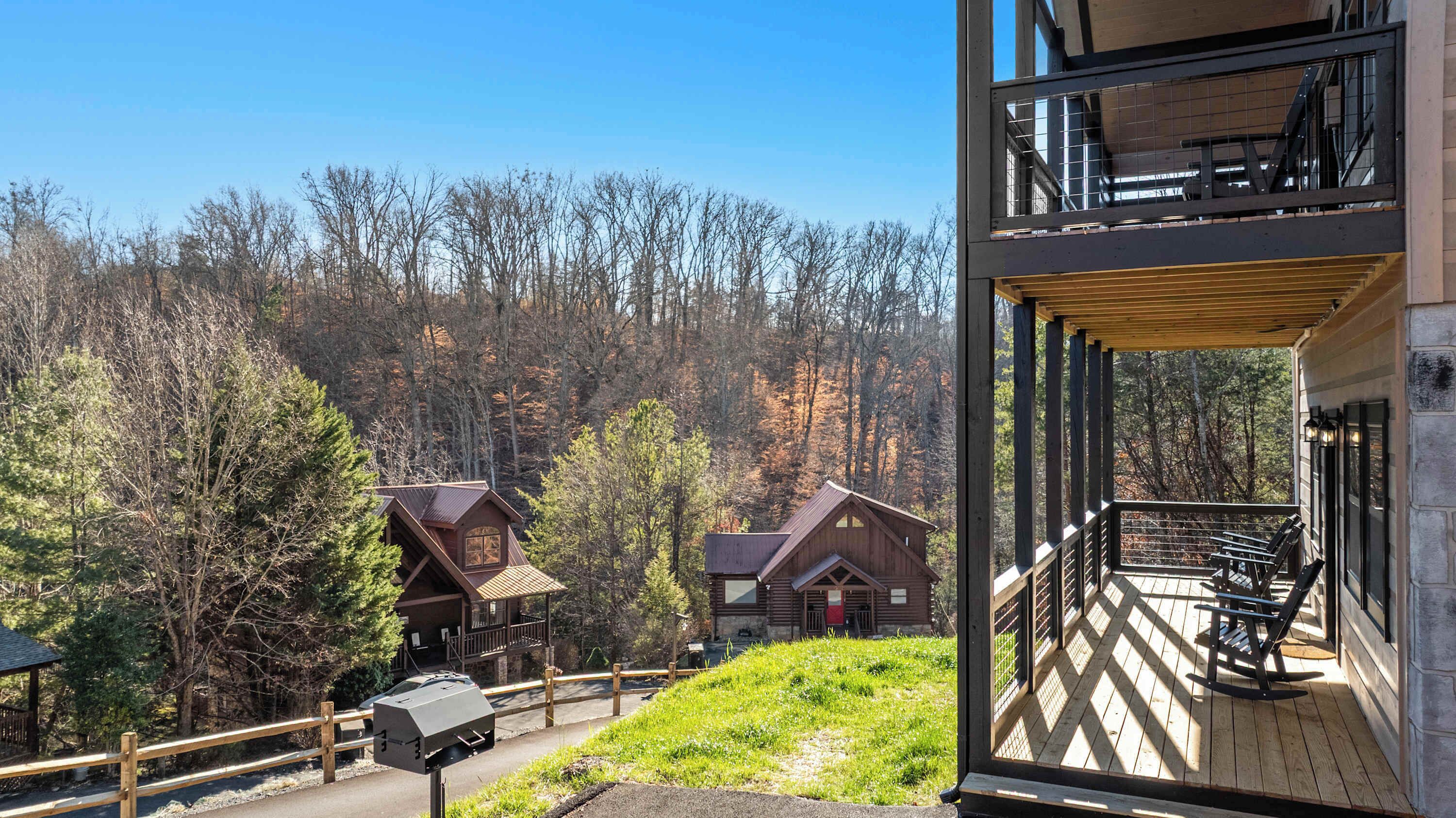 A cabin with a wooden deck and a view of forested hills.