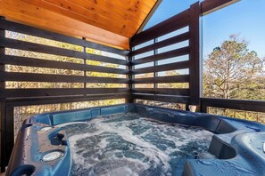 A hot tub with a wooden deck and a view of trees. - Modern Pigeon Forge Cabin | Hot Tub, Game Loft (Pigeon Forge)