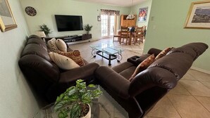 A living room with a sofa, a glass coffee table, and a television. - Summer 35% Off 4BR Pool Villa/Game Room (Kissimmee)