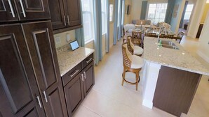 Une cuisine moderne avec des meubles en bois foncé, un plan de travail en granit et un îlot central doté de sièges.