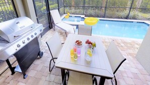 Une terrasse extérieure avec un barbecue, une piscine et un espace salon.