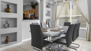 Un comedor moderno con una mesa blanca, sillas negras y una lámpara de araña.