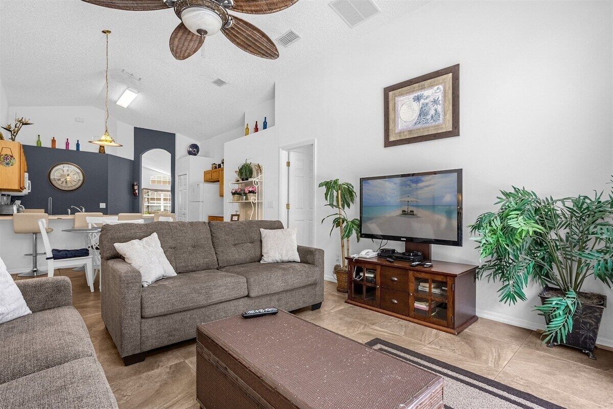 A living room with a sofa, TV, and plants.