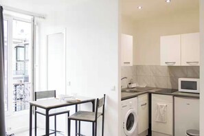 Une cuisine compacte équipée d’un lave-linge, d’un four à micro-ondes et d’un coin repas avec une table et des chaises.