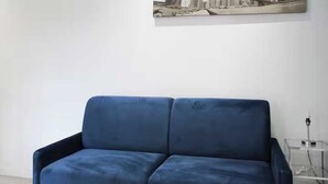 A blue sofa in a room with a small table and two potted plants. - Cosy Studio - 2P- Clichy (Clichy)