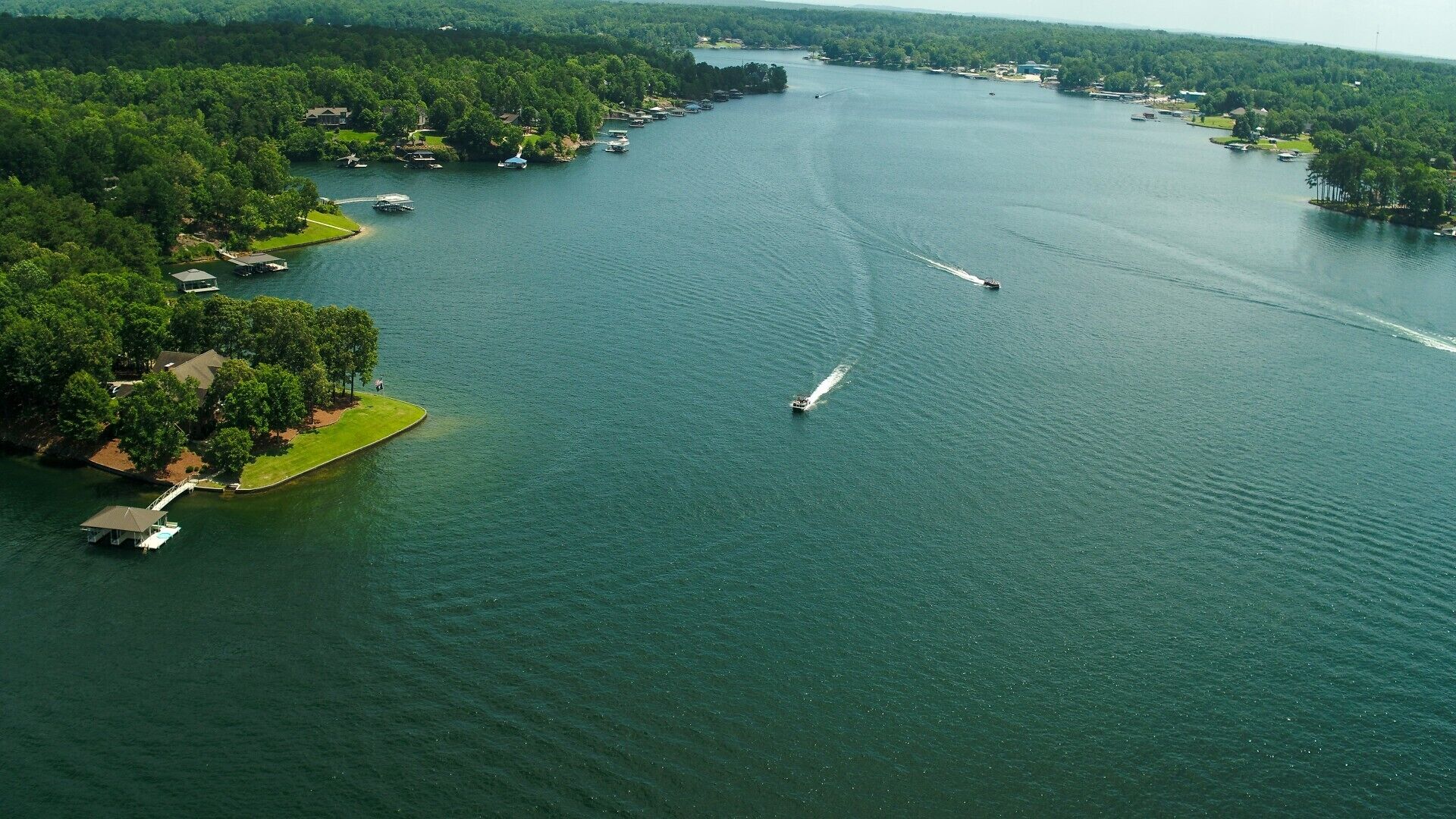Vue aérienne d’un lac, avec des bateaux, des quais et des maisons le long de la rive.