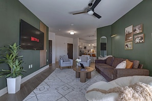 A modern living room with a flat-screen TV, two sofas, a coffee table, and a ceiling fan. - 2BR/2BA near Universal Kids, sleeps 6, patio (Frisco)