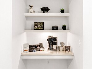 A kitchen counter with a coffee machine, cups, and a coffee bean bag. - Modern Apt Minutes to Universal (Frisco)