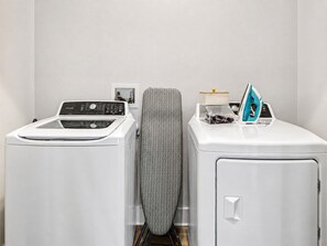 A laundry area with a front-loading washer, a dryer, and a utility cabinet. - Modern Apt Minutes to Universal (Frisco)