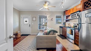 A modern kitchen with wooden cabinets, stainless steel appliances, and a ceiling fan. - The Hive | Patio | Walk Downtown | Beach Gear (St. Petersburg)