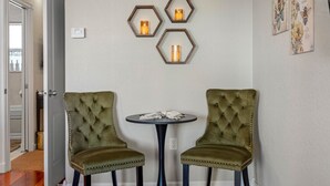 A room with two green upholstered chairs, a small round table with a white cloth, and three hexagonal wall sconces with candles. - The Hive | Patio | Walk Downtown | Beach Gear (St. Petersburg)