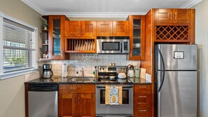 A modern kitchen with wooden cabinets, stainless steel appliances, and a built-in wine rack. - The Hive | Patio | Walk Downtown | Beach Gear (St. Petersburg)