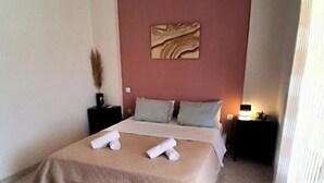 Ein Hotelzimmer mit Bett, Nachttisch, Wand-Klimaanlage und einem Fenster mit Vorhängen.