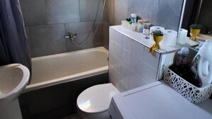 Ein kleines Badezimmer mit Badewanne, Toilette und einem kleinen Fenster.