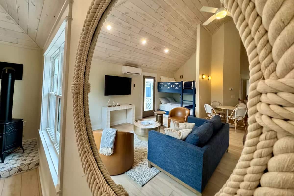 A cozy living room with a blue sofa, a round coffee table, and a TV mounted on the wall.