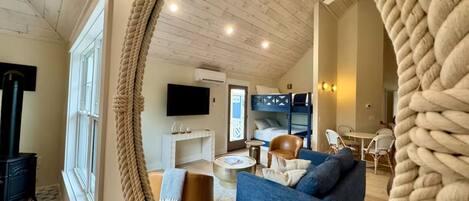 A cozy living room with a blue sofa, a round coffee table, and a TV mounted on the wall.