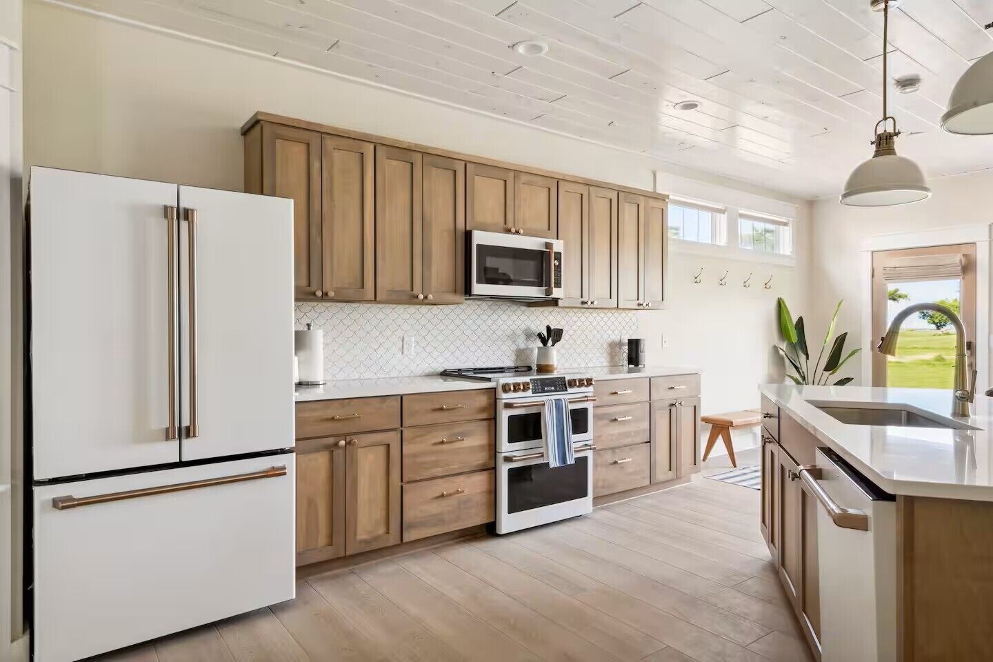 A modern kitchen with wooden cabinets, stainless steel appliances, and a large island with a sink.