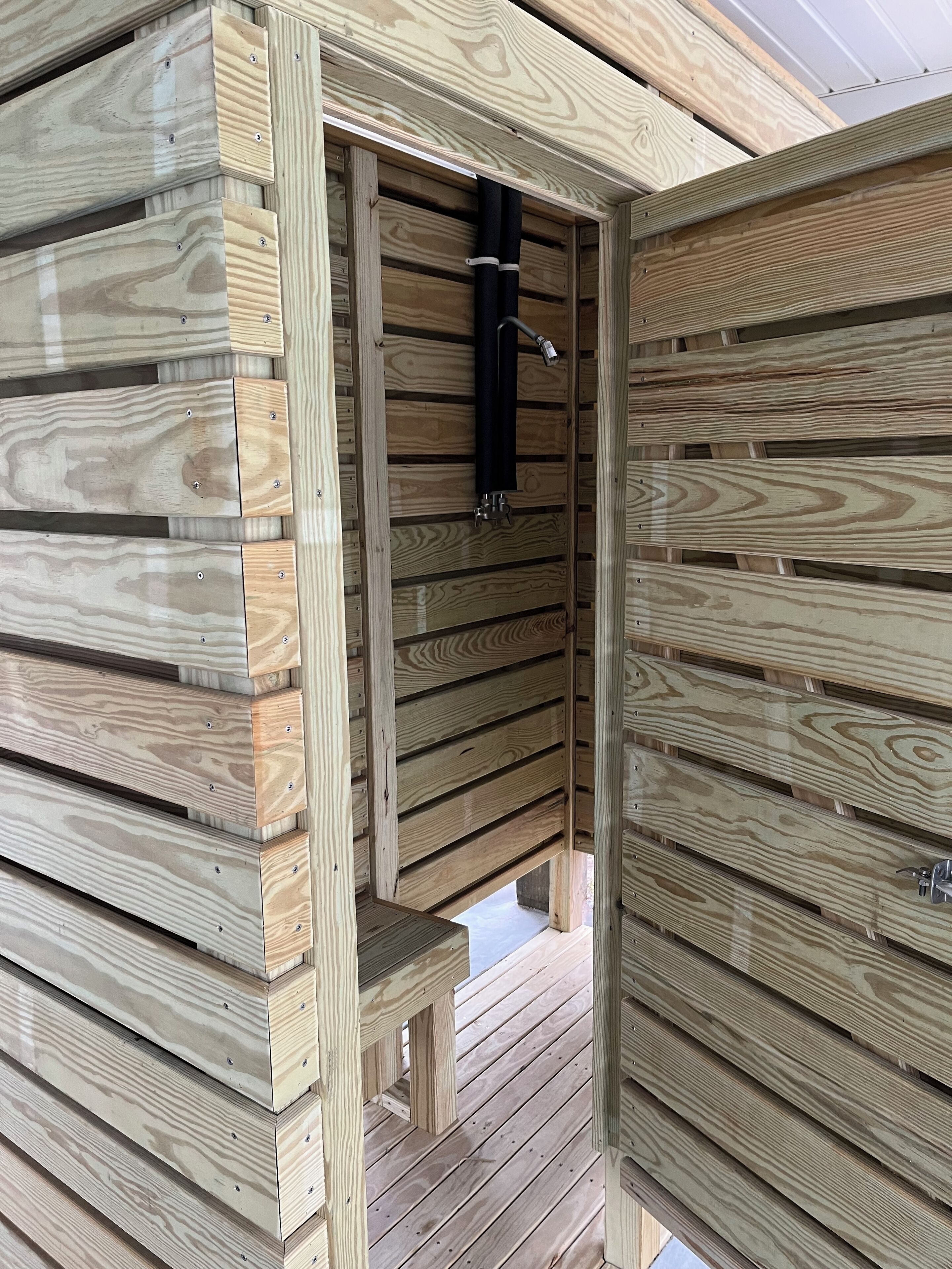 Una cabana de fusta amb un petit porxo i una mànega negra penjada a la paret.
