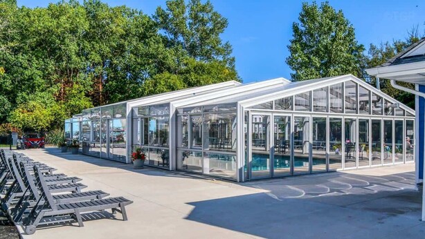 A modern greenhouse structure with transparent walls, a flat roof, and a concrete floor. - Harbor Splash - Steps to Indoor Pool (South Haven)