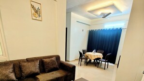 En moderne stue med en modulsofa, et sofabord og et spiseområde med bord og stole.