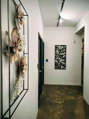 Ein Flur mit modernem Design, der sich durch eine dekorative Wandverkleidung mit metallischen Blumen und ein geometrisches Wandkunstwerk auszeichnet.