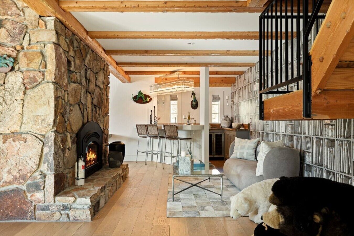 Un salón acogedor con chimenea de piedra, una zona de comedor con sillas, un sofá y un perro.