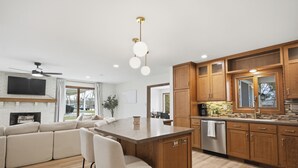 Una cocina moderna con armarios de madera, una isla central y un comedor con sofá y sillas.
