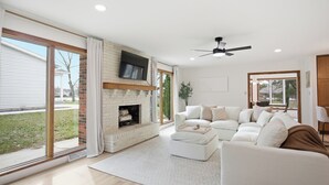 Una sala de estar moderna con chimenea, un sofá modular y un ventilador de techo.