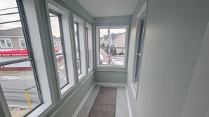 A narrow hallway with large windows, a grey carpet, and a view of a street with a McCoy Market sign.