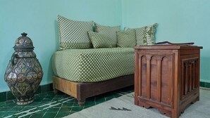 Ein Zimmer mit einem Bett, gestreiften Kissen, einem Nachttisch aus Holz und einer dekorativen Vase.