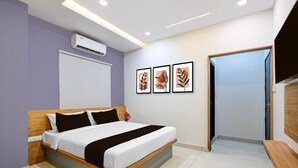 Habitación de hotel moderna con cama, unidad de aire acondicionado, obra de arte enmarcada y puerta que conduce a otra habitación.