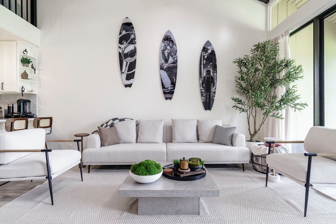 Sink into plush seating in your stylish living room, where surfboard art and natural light create the perfect coastal retreat atmosphere.