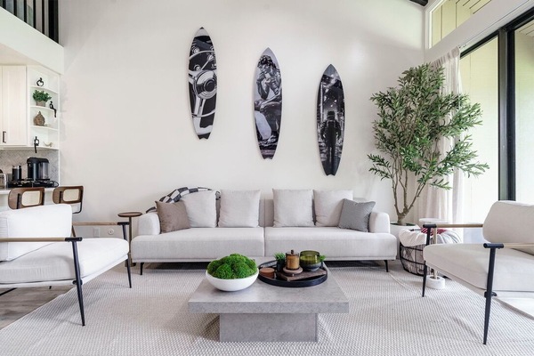 Sink into plush seating in your stylish living room, where surfboard art and natural light create the perfect coastal retreat atmosphere.
