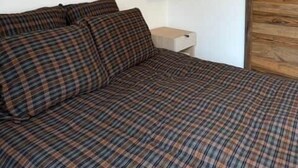 Ein Schlafzimmer mit Bett, Holz-Kopfteil, Nachttisch und Kleiderschrank.