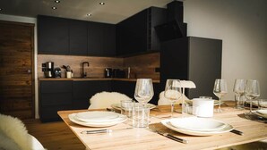 Ein Essbereich mit einem Holztisch, gedeckt für vier Personen, komplett mit Tellern, Gläsern, Besteck und einer weißen Kanne.