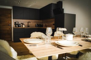 A dining area with a wooden table set for four, equipped with plates, glasses, cutlery, and a white pitcher. - The Courchevel Nests: APT 13, Le Praz (Courchevel)