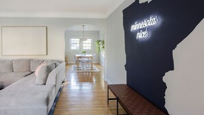 En moderne stue med en hjørnesofa, et spiseområde med bord og stole, samt en væg med silhuetten af Minnesota.