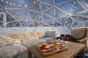 A cozy seating area with a wooden table set for a meal, featuring a charcuterie board and two glasses of red wine. - Snow Globe Lounge, Yoga Room, Game Room, Private Fenced Yard, Perfect Location (Minneapolis)