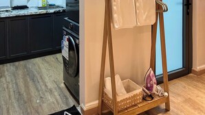 A compact kitchen with modern appliances, a wooden floor, and a small ironing station. - Cozy 1BR with balcony and Nguyen Hue Walking Street view (Thành phố Hồ Chí Minh)